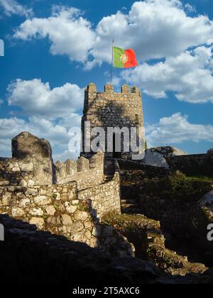 Mittelalterliches Castelo dos Mouros, auch bekannt als Schloss der Mauren in Sintra, Portugal. Wachturm mit portugiesischer Flagge und Verteidigungsmauer Stockfoto