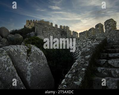 Mittelalterliches Castelo dos Mouros, auch bekannt als Schloss der Mauren in Sintra, Portugal. Wachtturm und Verteidigungsmauer klettern bei Sonnenuntergang auf den Bergrücken Stockfoto