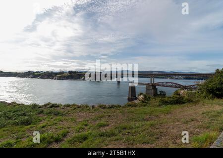 Bridging the Gap: Malerischer Blick auf eine Brücke über einen Fluss unter einem bewölkten Himmel Stockfoto