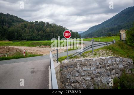 Das Stoppschild steht auf einem leeren Weg, der durch eine ländliche Landschaft führt. Die von Bergen und Feldern umgebene Überlandstraße Sloweniens. Bewölkter Tag Stockfoto