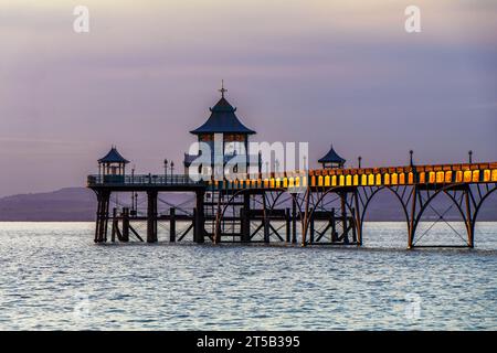 Clevedon Pier bei Flut, wobei die Seitenverkleidungen des Piers das letzte Sonnenlicht auffangen Stockfoto