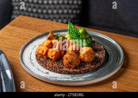 Buddha-Schüssel mit Quinoa, Brokkoli und Pilz-Tofu-Sauce. Gesunde Ernährung, gesunde Lebensweise, vegane Ernährung, vegetarische Ernährung. Essen in einem Restaurant serviert Stockfoto