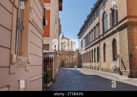 Eine Straße in Parma und im Hintergrund die entgliederte Renaissancekirche San Marcellino, Italien. Stockfoto