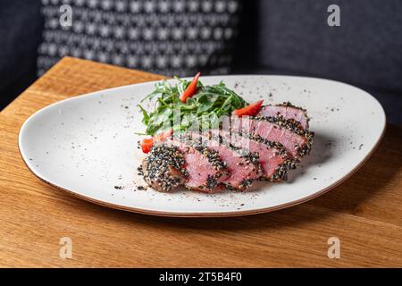 Thunfisch-Tataki in Sesam mit Quinoa und Spinat. Gesundes Essen, Nahaufnahme. Serviert Speisen in einem Restaurant Stockfoto