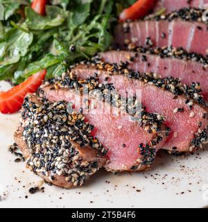 Thunfisch-Tataki in Sesam mit Quinoa und Spinat. Gesundes Essen, Nahaufnahme. Serviert Speisen in einem Restaurant Stockfoto