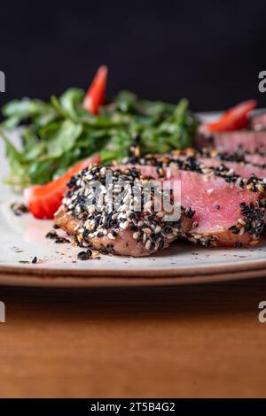 Thunfisch-Tataki in Sesam mit Quinoa und Spinat. Gesundes Essen, Nahaufnahme. Serviert Speisen in einem Restaurant Stockfoto