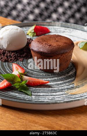 Lavakuchen mit Vanillesauce mit frischen Erdbeeren, Eiskugel. Gesundes Essen, Nahaufnahme. Serviert Speisen in einem Restaurant. Stockfoto