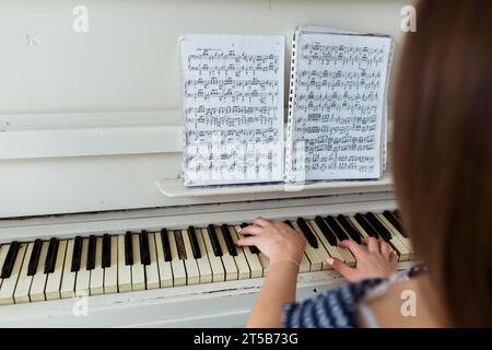 Nahaufnahme einer Frau, die Klavier spielt, indem sie Notenblatt-Klavier sieht Stockfoto