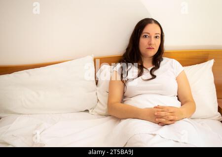 Schuss einer Frau, die im Bett liegt und ignorierte und verlassen wurde. Frau allein in ihrem Bett mit Kopierraum. Stockfoto