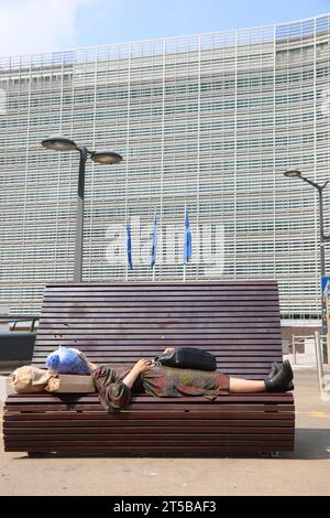 Brüssel, B, Belgien - 18. August 2022: Büros im Palast Berlaymont und eine obdachlose Frau, die auf der Bank schläft Stockfoto