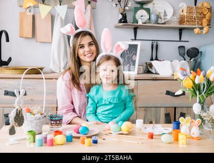 Glückliche Frau, die mit Hasenohren in der Nähe der ostereier sitzt Stockfoto