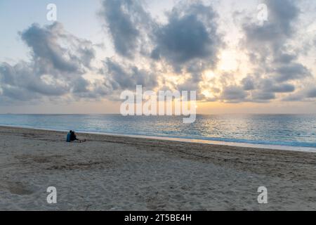 Ein Paar im Urlaub, das am Strand sitzt und den Sonnenuntergang genießt. Stockfoto