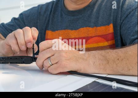 Ein Mann zieht einen Reißverschluss fest, um eine Solarpaneel-Verbindung zu sichern Stockfoto