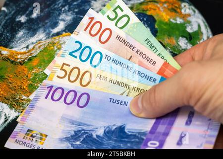 Norwegisches Geld, Wechselkurse, Weltwirtschaft, Finanzwirtschaftskonzept, norwegische Kronen auf dem Hintergrund der Weltkarte Stockfoto