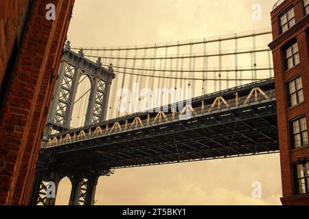 Ein atemberaubendes Stockfoto der berühmten Manhattan Bridge, eingerahmt vom lebhaften Viertel DUMBO in Brooklyn. Das Foto zeigt das Neo-Gothi der Brücke Stockfoto