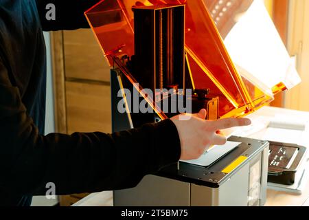 Mann, der einen 3D-Harzdrucker vor der Verwendung vorbereitet Stockfoto