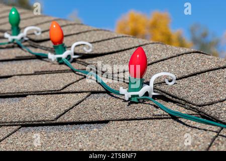 Hängende Weihnachtsbeleuchtung an Dachschindeln. Feiertagsdekoration Sicherheits-, Licht- und Unfallverhütungskonzept. Stockfoto