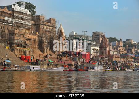 VARANASI, INDIEN - 13. November 2022: Blick von einem Boot aus gleitet durch das Wasser auf dem Ganges Fluss entlang der Küste von Varanasi. Stockfoto