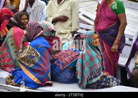 VARANASI, INDIEN - 13. November 2022: Frau sitzt nachts in der Nähe eines zeremoniellen Feuers in der Nähe des Heiligen Ganges. Manikarnika Ghat Stockfoto