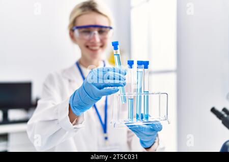 Junge blonde Wissenschaftlerin, die Reagenzgläser im Labor analysiert Stockfoto