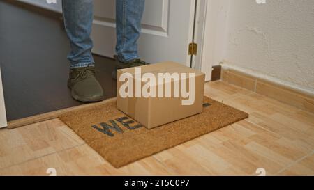 Ein junger latino, der zu Hause ein Paket auf den Fußabtreter legt Stockfoto