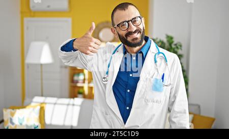 Junger hispanischer Arzt, der in der Klinik Daumen hoch hält Stockfoto