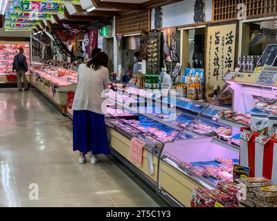 Japan, Kyushu, Imi. Kleines Lebensmittelgeschäft, Käufer, die Fleisch- und Meeresfrüchteauswahl prüfen. Stockfoto