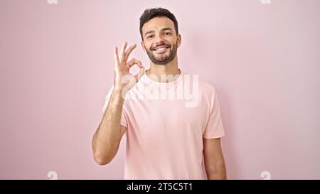 Junger hispanischer Doktor, der eine gute Geste über isoliertem rosa Hintergrund macht Stockfoto