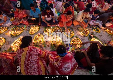 Dhaka, Bangladesch. November 2023. Hindugeweihte sitzen mit Prodip (Lichtern) und beten zu Gott für das Wohlergehen der Familie vor dem Shri Shri Lokanath Brahmachari Ashram Tempel, Swamibag, Dhaka während des Kartik Brati oder Rakher Upobash, einem religiösen hinduistischen Fastenfest, das jährlich in der letzten Hälfte des bengalischen Monats Kartik organisiert wird. Gläubige sitzen mit Essen und Kerzen und beten ernsthaft zu Gott, bevor sie das Fasten brechen. Lokenath Brahmachari, der Baba Lokenath genannt wird, war ein Hindu-heiliger und Philosoph aus Bengalen aus dem 18. Jahrhundert. Lokenath Brahmachari-Gläubige beten mit Licht, um ihre Familie zu retten Stockfoto