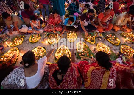 Dhaka, Bangladesch. November 2023. Hindugeweihte sitzen mit Prodip (Lichtern) und beten zu Gott für das Wohlergehen der Familie vor dem Shri Shri Lokanath Brahmachari Ashram Tempel, Swamibag, Dhaka während des Kartik Brati oder Rakher Upobash, einem religiösen hinduistischen Fastenfest, das jährlich in der letzten Hälfte des bengalischen Monats Kartik organisiert wird. Gläubige sitzen mit Essen und Kerzen und beten ernsthaft zu Gott, bevor sie das Fasten brechen. Lokenath Brahmachari, der Baba Lokenath genannt wird, war ein Hindu-heiliger und Philosoph aus Bengalen aus dem 18. Jahrhundert. Lokenath Brahmachari-Gläubige beten mit Licht, um ihre Familie zu retten Stockfoto