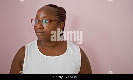 Ernsthafte aftere afroamerikanische Frau, die zur Seite blickt, zeigt eine coole, entspannte Atmosphäre, isoliert vor einer leuchtend rosa Wand. Lifestyle in Übergröße Stockfoto