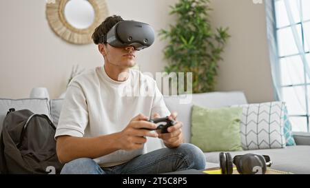 Der junge hispanische Teenager taucht zu Hause in das Gaming-Universum ein, indem er eine Virtual-Reality-Brille und einen Joystick verwendet, und lebt so entspannt und doch konzentriert 3 Stockfoto