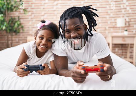 Vater und Tochter spielen Videospiel und liegen im Bett im Schlafzimmer Stockfoto