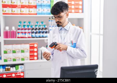 Junger hispanischer Mann Apotheker Scannen Pillen Flasche in der Apotheke Stockfoto