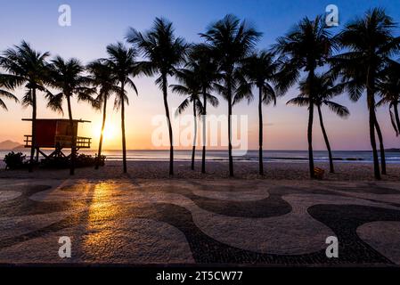 Palmen und Rettungsschwimmerposten am Copacabana Beach am Sonnenaufgang und berühmtem Bürgersteig Mosaic Stockfoto