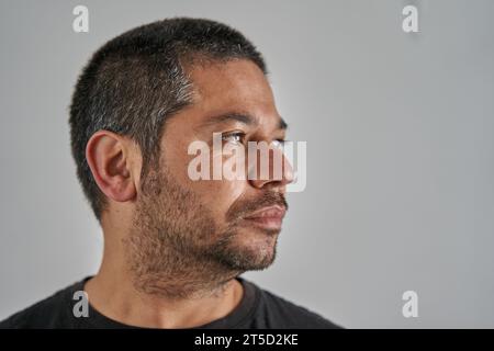 Porträt eines nach rechts schauenden Mannes auf neutralem Hintergrund. Mann in einem leeren Raum Stockfoto