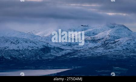 Ein Flugzeug startet vor dem Hintergrund der Berge über der norwegischen Stadt Tromso Stockfoto