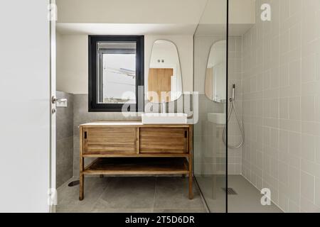 Badezimmer in einem Apartment mit Holzmöbeln mit Schiebetüren und schwebendem Waschbecken aus weißem Porzellan Stockfoto