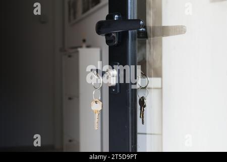 Schlüssel hängen vom Schloss einer offenen Haustür. Haussicherheit, Immobilienkonzept. Stockfoto