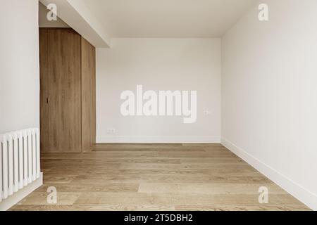 Leeres Zimmer mit weiß gestrichenen Wänden, Holzfußboden und Kleiderschrank Stockfoto