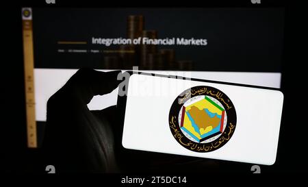 Person, die ein Mobiltelefon mit dem Logo des Gulf Cooperation Council (GCC) der Arabischen union vor der Webseite hält. Schwerpunkt auf dem Display des Telefons. Stockfoto
