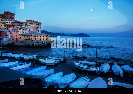 Fantastischer Blick auf den Sonnenuntergang vom alten Fischerdorf Boccadasse in Genua Vorort und auf den Mond am Himmel, viele Boote, die auf dem Boden rosa und gelbe Fishe schützen Stockfoto