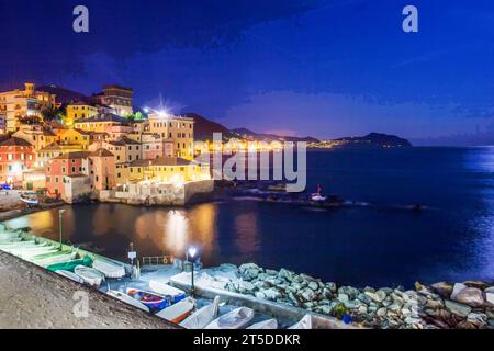 Fantastischer Blick auf den Sonnenuntergang vom alten Fischerdorf Boccadasse (mit rosa und gelben Häusern auf Klippen im Vorort Genua. Nachtblick und italienische Riviera B Stockfoto