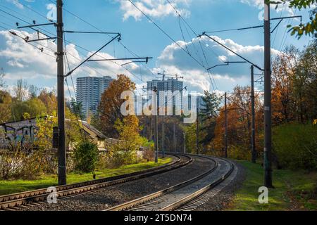 Eisenbahnstrecke im Stadtpark mit hohen Hochhäusern im Hintergrund. Herbst in Kiew, Ukraine Stockfoto