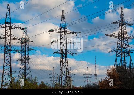 Mehrere Powerline-Stütztürme gegen den blauen Himmel mit Wolken. Stromnetz Stockfoto