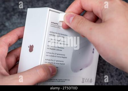 Jurmala, Lettland - 21 09 2023: Das neue Apple-Gadget wird entpackt. Frau reißt mit neuen Kopfhörern – AirPods Pro 2 Generation – einen Schutzstreifen in einer Box ab. Stockfoto