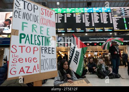 London, Großbritannien. November 2023. Aktivisten veranstalten einen Sit-Down-Protest in der Charing Cross Station, nachdem Zehntausende palästinensische Unterstützer am vierten Samstag in Folge durch London zogen und einen Waffenstillstand und ein Ende der britischen Unterstützung der Belagerung und des Krieges gegen Gaza durch Israel gefordert hatten, worauf UN-Organisationen warnen. steht vor einer humanitären Katastrophe. Der Protest kommt, als Israel Nahrungsmittel, Wasser und Strom abschneidet und Gaza einem intensiven Bombardement aussetzt. Quelle: Ron Fassbender/Alamy Live News Stockfoto