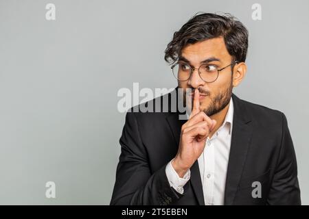 Bitte sei ruhig. Indischer Geschäftsmann drückt Zeigefinger auf die Lippen macht Stille Geste Zeichen sagt nicht geheim, hört auf, Klatsch zu reden, vertrauliche Privatsphäre. Arabian man Typ isoliert auf grauem Hintergrund Stockfoto