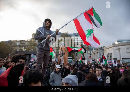 London, Großbritannien. November 2023. Ein junger Mann schwingt palästinensische und libanesische Flaggen auf dem Trafalgar-Platz, auf dem Tausende zu einem Waffenstillstand in Gaza aufgerufen haben. Der Protest folgt auf den jüngsten Ausbruch der Gewalt zwischen Hamas und Israel. Quelle: Kiki Streitberger/Alamy Live News Stockfoto