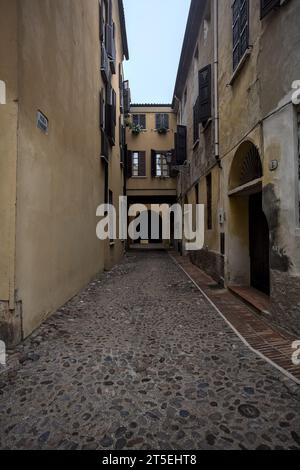 Kopfsteinpflaster und enge Gasse zwischen Gebäuden an einem bewölkten Tag in einer italienischen Stadt Stockfoto